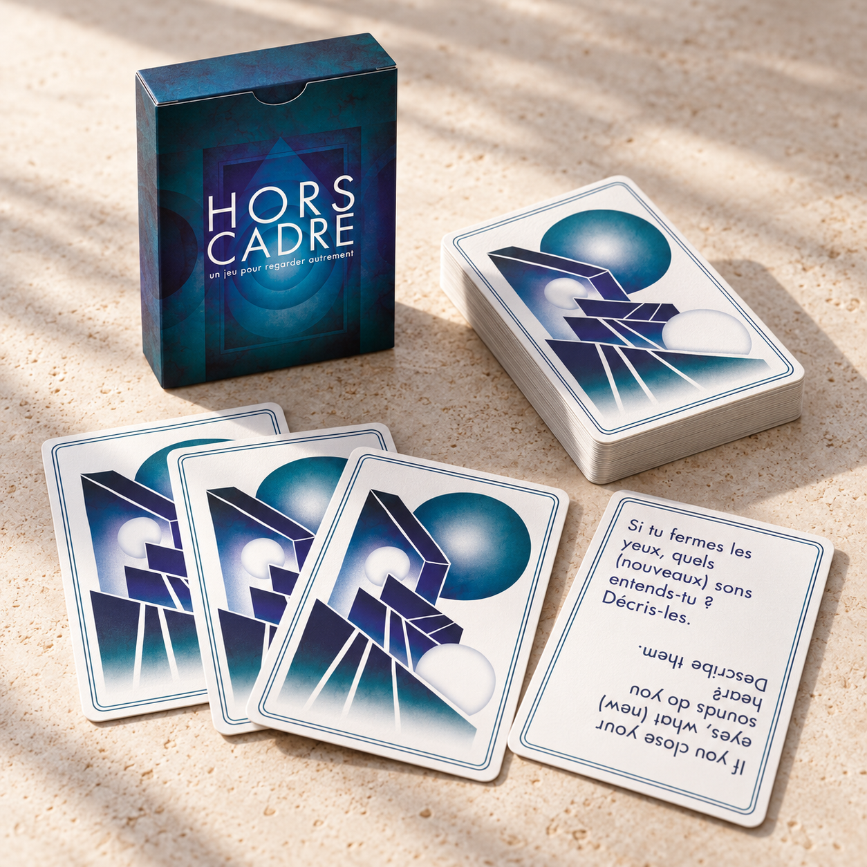 Mise en scène imaginée du jeu Hors cadre : boîtier bleu, paquet et cartes déployées sur une table claire.